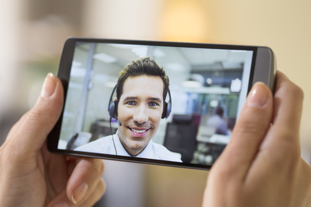 Closeup of a female hand holding a smart phone DURING a skype videoの写真素材