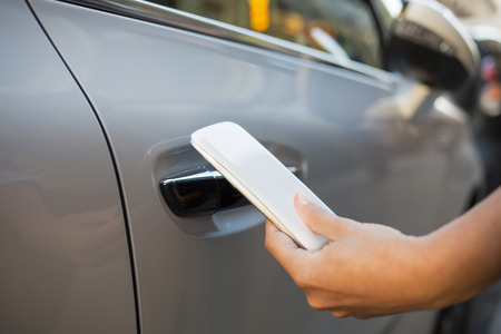 Woman opening her car with her smart phoneの写真素材