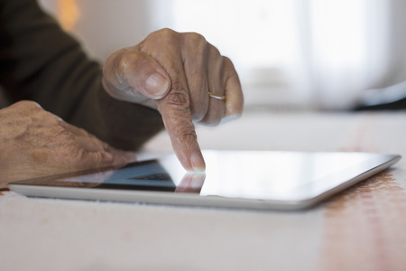 Female mature writing digital tablet indoors closeupの写真素材