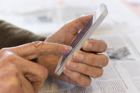 Female mature writing cell phone indoors closeupの写真素材