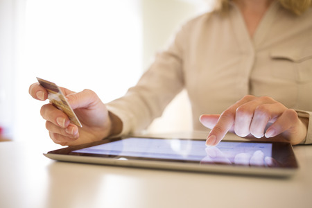 Woman shopping online using tablet pc and credit card at homeの写真素材