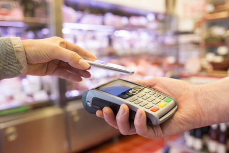 Woman paying with NFC technology on mobile phone, in supermarketの写真素材