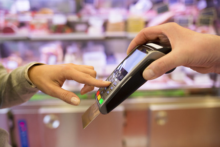 Woman hand with credit card swipe through terminal for sale, in marketの写真素材