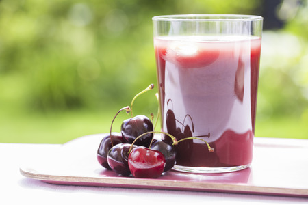Glass of Cold cherries juice in gardenの写真素材