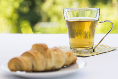 Croissant and hot Tea in gardenの写真素材