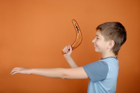 Boy with a boomerang on an orange backgroundの写真素材