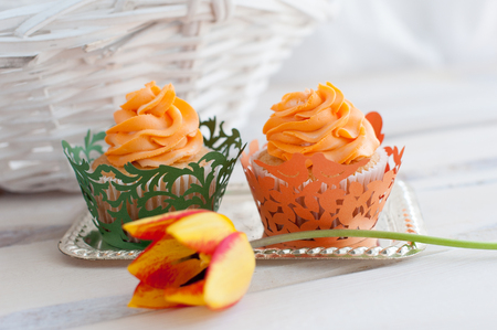 Two delicious cupcakes with orange cream and tulipの写真素材