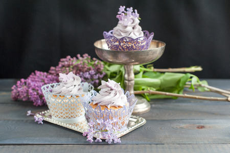 Three delicious cupcakes on a table with flowersの写真素材