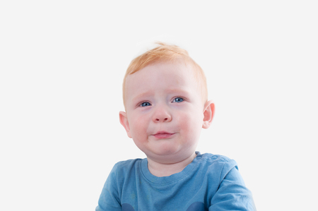 Crying redhead boy in blue tank top on the white backgroundの写真素材