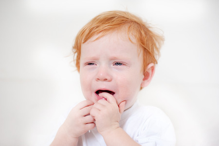 Miserable redhead boy crying on the white backgroundの写真素材
