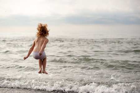 Red-haired girl is jumping over the wavesの写真素材