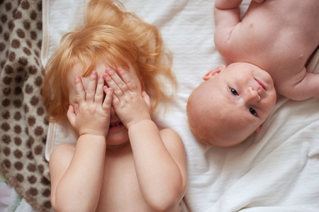Red-haired brother and sister are lying on the bedの写真素材