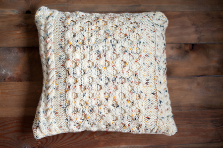 Knitted pillow on a wooden background