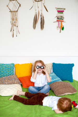 Children play on the bed among pillowsの写真素材