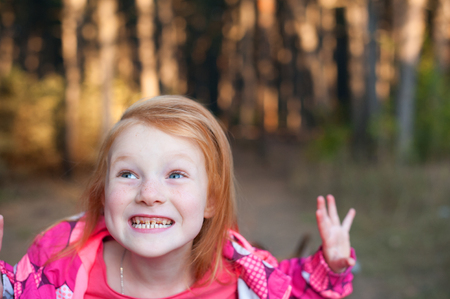Red-haired girl showing teeth in the forestの写真素材
