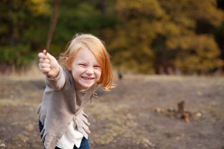 Red-haired girl is playing and laughing at the forestの写真素材