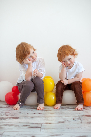 Funny redhead brother and sister are sitting on balloonsの写真素材