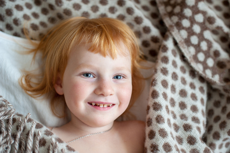 A girl with caries smiles on the bedの写真素材
