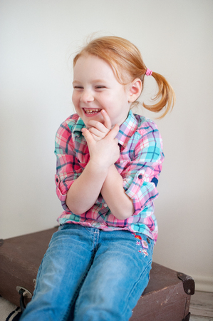A girl in a plaid shirt and jeans laughsの写真素材