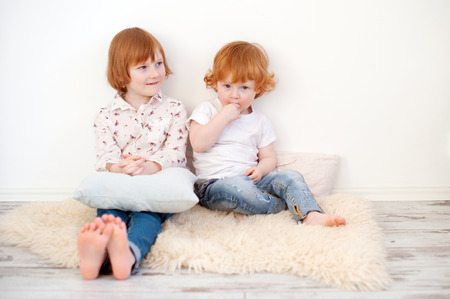 Sister and brother are sitting on the floorの写真素材