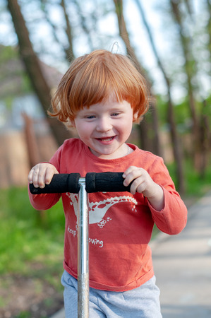 A boy with a smile rides a scooterの写真素材