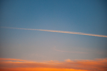 Bright sunset sky with clouds and airplaneの写真素材