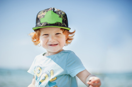 Smiling child in a cap on the background of the sea