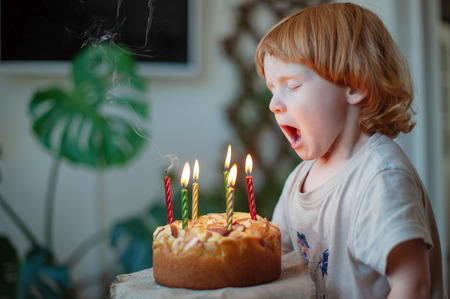Redhead child blowing out candles on a birthday cake