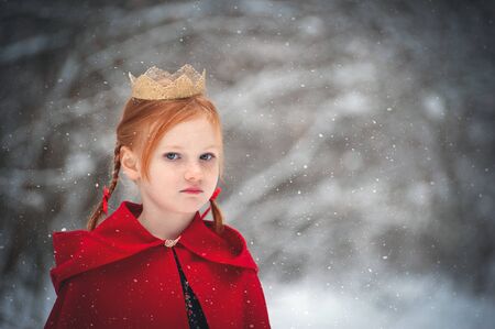 Girl in a red coat with a gold crown on her headの写真素材