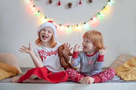 Brother and sister sit on a bed in a Christmas settingの写真素材