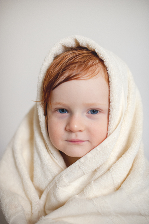 Baby after a bath, with wet hair in a towelの写真素材