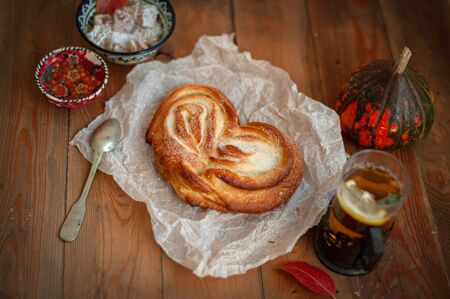Freshly baked appetizing bun and tea on the boardの写真素材