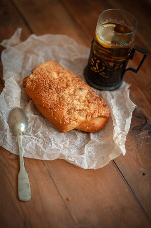 Freshly baked appetizing bun and tea on the boardの写真素材