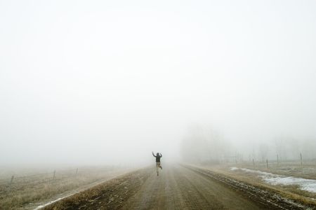 Walking alone on a saskatchewan road in the fog, and jumping for joy.の写真素材