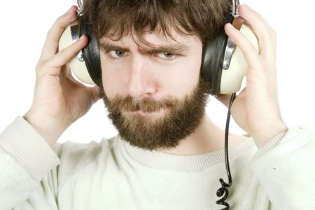 A young man looking sceptical while listening to music on headphones. Isolated on white with .の写真素材