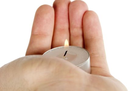 A simple tea light candle being held in a hand, isolated on whiteの写真素材