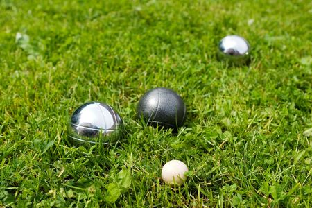 Bocce balls sitting in the green grass, close to the target. -shallow depth of field.-の写真素材