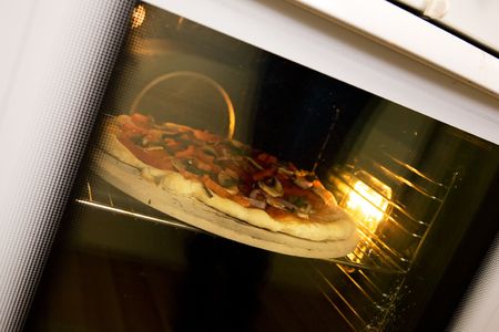 A homemade pizza baking in an ovenの写真素材