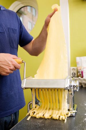 Fettuccine coming out of a manual pastamachine - shallow depth of field with focus on the pastaの写真素材