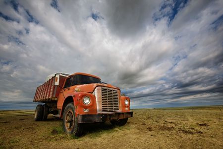 An old farm truck against a dramatic prairie landscapeの写真素材