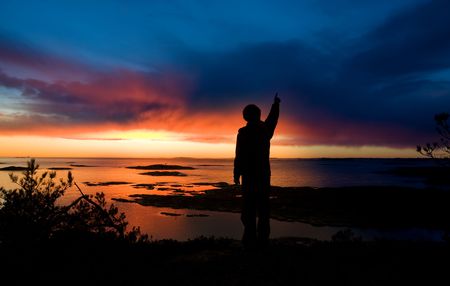 A person standing by the ocean pointing into the distanceの写真素材