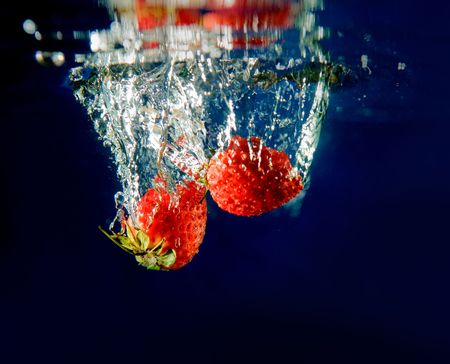 Two Strawberries splashing in waterの写真素材