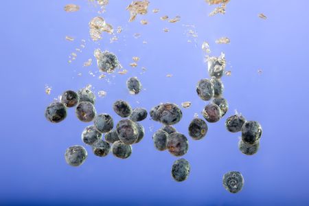 Blueberries floating in water with bubblesの写真素材