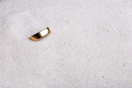 A lost ring hiding in soft white sand.の写真素材