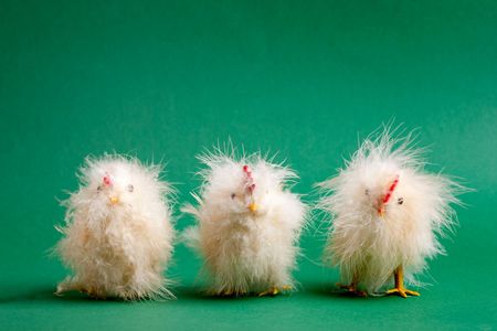 Three funny little easter decorations lined up on a green backgroundの写真素材