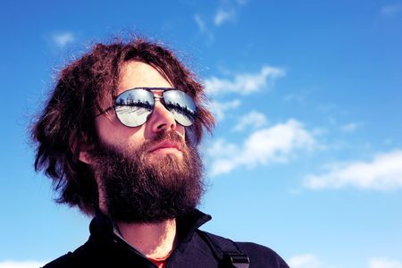 A male with a full beard and retro sunglasses standing in a winter landscape - cross processedの写真素材