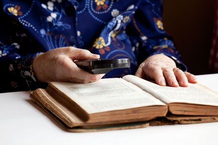 An elderly woman reading a very old bookの写真素材