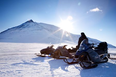 Three snowmobiles and a winter landscape with mountainの写真素材