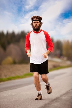 A tired retro style jogger running on a road outdoorsの写真素材