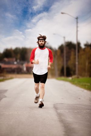 A tired retro style jogger running on a road outdoorsの写真素材